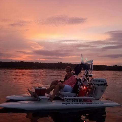 a group of people on a boat in the water at sunset