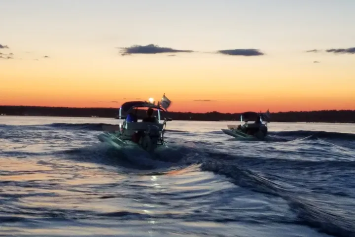 Boaters driving vessel into sunset