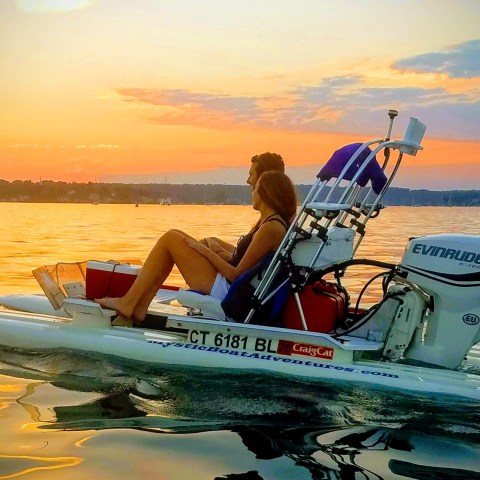 a person sitting on a boat in the water at sunset